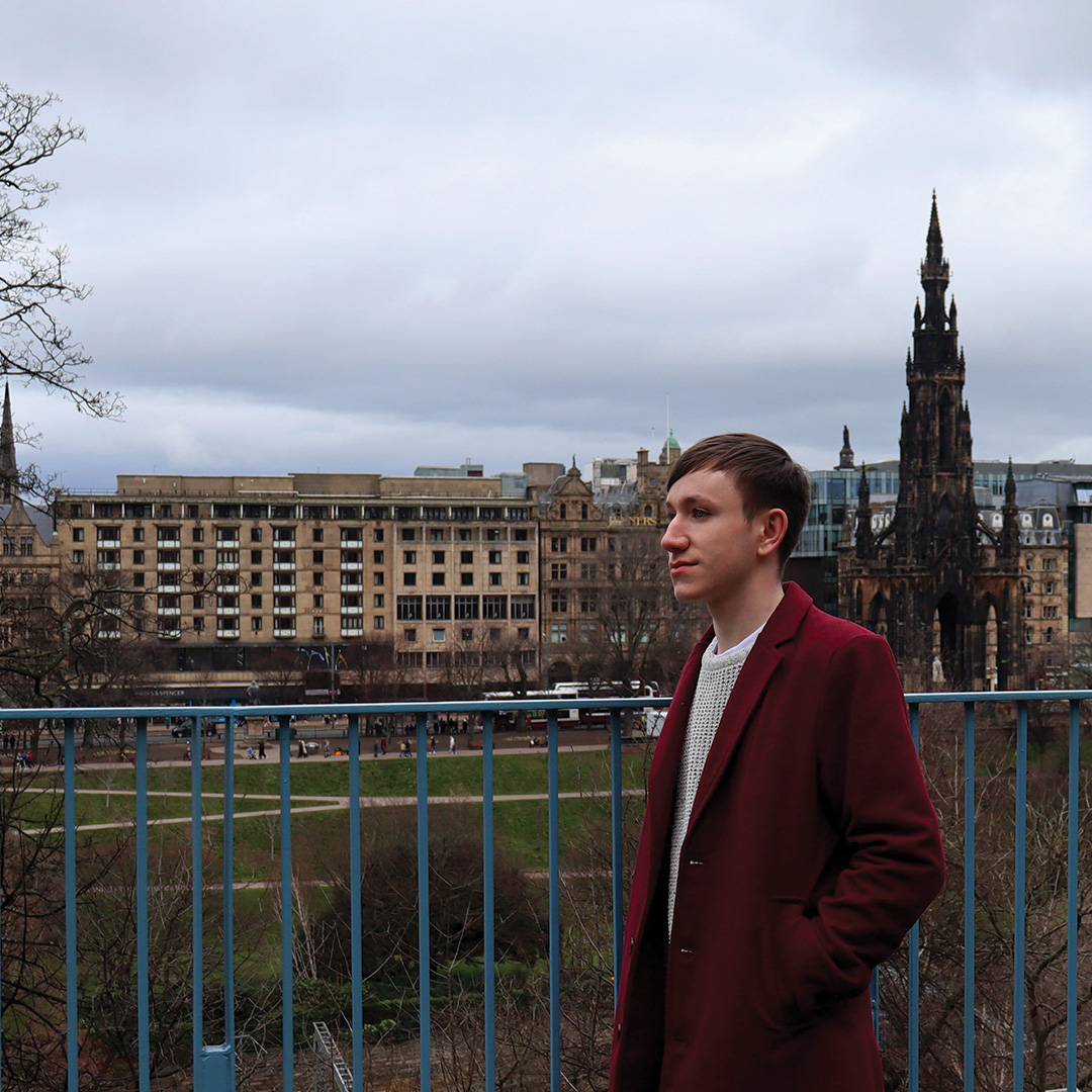 Ben stands outside, buildings in the background 