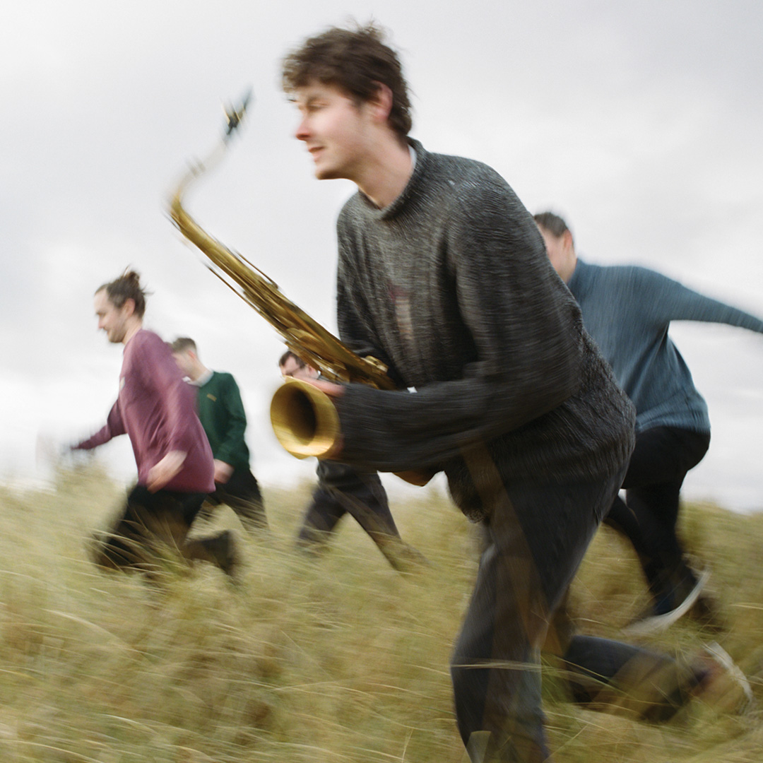 Matt and his band running with their instruments  